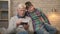 Grandfather and grandson are sitting on the couch using a smartphone, playing on a smartphone. Young fat boy and