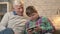 Grandfather and grandson sitting on the sofa using a smartphone, speaking, a fat child is playing on a smartphone. Young