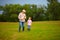 Grandfather and grandson walking through the green field, with puppy in hands