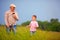 Grandfather with grandson walking through the summer field