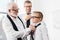 grandfather helping his grandson tie a necktie while father