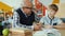 Grandfather helping junior child with homework talking sitting at desk together