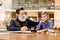 Grandfather his grandson, teacher and student, sitting at the table in ancient library, boy is interested in reading