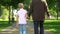 Grandfather holding hand of grandson, walking together, support during life