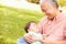 Grandfather Holding Sleeping Grandson In Park