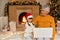 Grandfather hugs his grandchild while sitting on floor and holding laptop on knees, child wearing santa hat looks at screen, pose