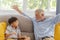 Grandfather and little cute grandson playing touchscreen tablet PC together on sofa in their house