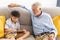 Grandfather and little cute grandson playing touchscreen tablet PC together on sofa in their house