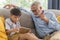 Grandfather and little cute grandson playing touchscreen tablet PC together on sofa in their house