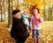 The grandfather with little granddaughters in the autumn park