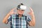 Grandfather looks into VR glasses, hand gestures, on a gray background