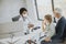 Grandfather with protective facial masks with granddaughter at black female doctor