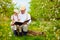 Grandfather reading a book to his grandson, in blooming garden