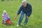 The grandfather rolls the granddaughter on the toy car (focus on