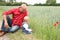 Grandfather sits next to a small child in jeans on the grass, the concept of family relationships, human-nature interactions,