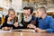 Grandfather sitting with grandchildren at the table in library, reading and telling book fairy tale story. Happy excited