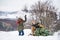 Grandfather and small girl getting a Christmas tree in forest, having fun.