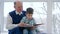 Grandfather teaches grandson to read book at home