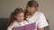 Grandfather teaches his granddaughter to read books. Family educational concept. An elderly man and a little girl leaf