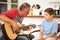 Grandfather Teaching Grandson To Play Guitar