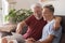 Grandfather and teenage grandson sitting together on the couch at home looking with fun at the same laptop and smiling - sharing