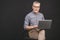 Grandfather using modern technologies. Smiling old businessman in eyeglasses using laptop computer isolated over black background