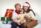 Grandma, daughter and granddaughter dressed in santa hat with gift boxes sit on sofa, white background. New year eve and christmas