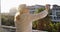 Grandma with deep wrinkles stands on the balcony and waves her hand.