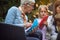 Grandma is playing with granddaughter with paper boats sitting outside, focused. Copy space