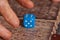 Grandma rolls a blue dice.Social game. Throwing a blue cube