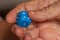 Grandma rolls a blue dice.Social game. Throwing a blue cube