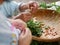 Grandma`s hands preparing vegetables for cooking with defocus foreground of her little granddaughter`s hands learning to do it too