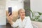 Grandma Taking Selfies at Home in the Livingroom. Close Up Portrait of Happy Cheerful Delightful Charming Beautiful Elderly Lady