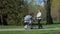 Grandma walks with stroller on road in city park in spring