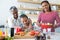 Grandmother assisting granddaughter to chop vegetables in kitchen