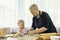 Grandmother in black apron teaches her cute little granddaughter make cookies