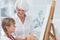 Grandmother and cute granddaughter painting together