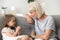 Grandmother and cute granddaughter relax on couch talking