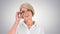 Grandmother in glasses and with gray hair happy and smiling looking to camera on gradient background.