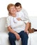 Grandmother and grandchild family portrait on white background, happy people sit on sofa.