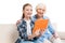 Grandmother and grandchild using digital tablet and sitting on sofa