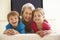 Grandmother And Grandchildren Watching Widescreen TV At Home