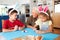 Grandmother With Grandchildren Wearing Rabbit Ears Decorating Easter Eggs At Home Together