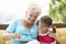 Grandmother And Granddaughter Reading Book On Garden Seat