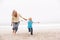 Grandmother And Granddaughter Running Along Beach