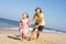 Grandmother And Granddaughter Running Along Beach