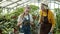 Grandmother and granddaughter talking and writing in notebook checking plants in greenhouse