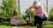 Grandmother and granddaughter watering plant in garden