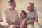 Grandmother and grandfather sitting on bed together with their granddaughter.