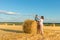 A grandmother with a grandson puts on a haystack on a field on a sunny day.  Grandson delighted, they have fun together